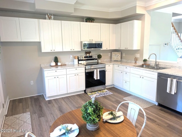 3 Sloop St, Swansboro, NC 28584 - kitchen featuring appliances with stainless steel finishes, crown molding, light stone countertops, white cabinets, and dark wood finished floors