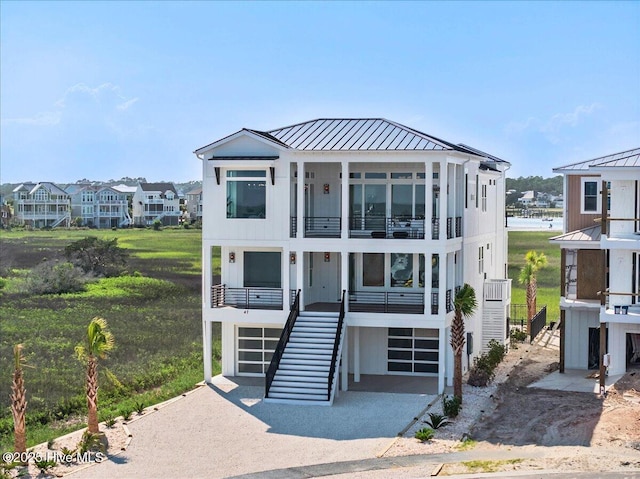 47 Grande View Dr, Ocean Isle Beach, NC 28469 - raised beach house featuring a balcony, a standing seam roof, stairs, a garage, and a metal roof