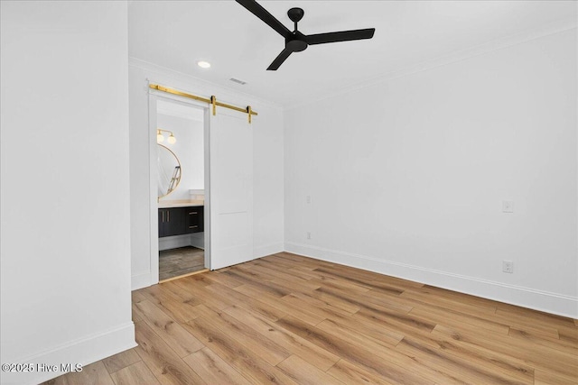 47 Grande View Dr, Ocean Isle Beach, NC 28469 - unfurnished bedroom featuring a barn door, crown molding, light wood-style floors, ensuite bathroom, and ceiling fan