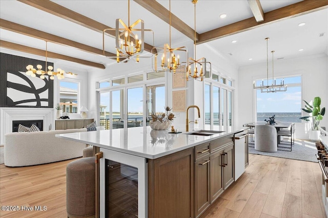 47 Grande View Dr, Ocean Isle Beach, NC 28469 - kitchen featuring a chandelier, beverage cooler, beam ceiling, light wood-style flooring, and an island with sink