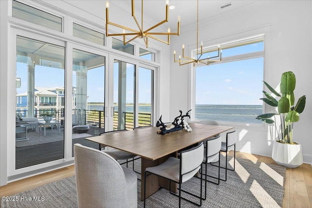 47 Grande View Dr, Ocean Isle Beach, NC 28469 - dining room with a chandelier, a water view, light wood finished floors, and healthy amount of natural light