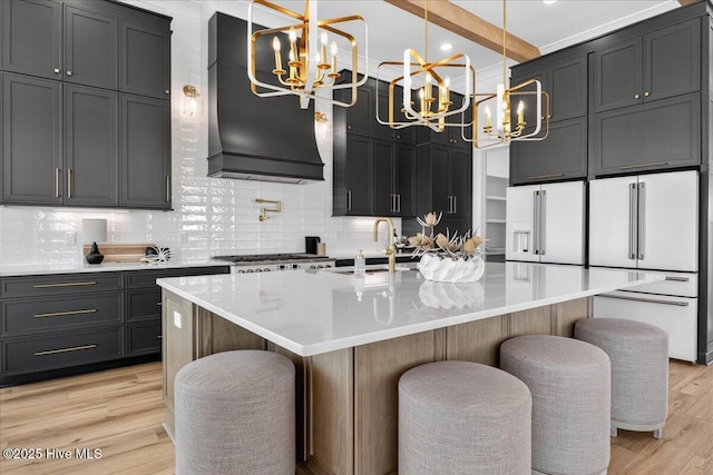 47 Grande View Dr, Ocean Isle Beach, NC 28469 - kitchen featuring a chandelier, decorative backsplash, light wood-style floors, freestanding refrigerator, and light countertops