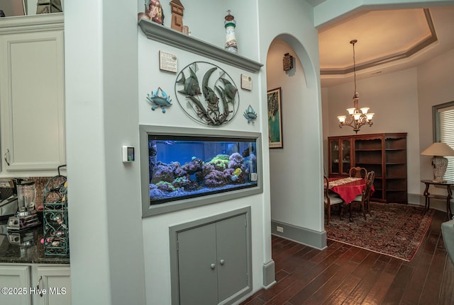 6601 Annesbrook Pl, Ocean Isle Beach, NC 28469 - hallway featuring a chandelier, dark wood-style flooring, a tray ceiling, and arched walkways