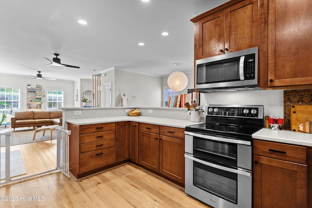 117 S 8th St, Wilmington, NC 28401 - kitchen featuring stainless steel appliances, a peninsula, light countertops, brown cabinetry, and ornamental molding