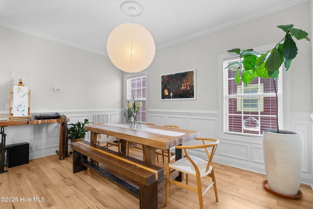 117 S 8th St, Wilmington, NC 28401 - dining space with a wainscoted wall, ornamental molding, light wood-style flooring, and a decorative wall
