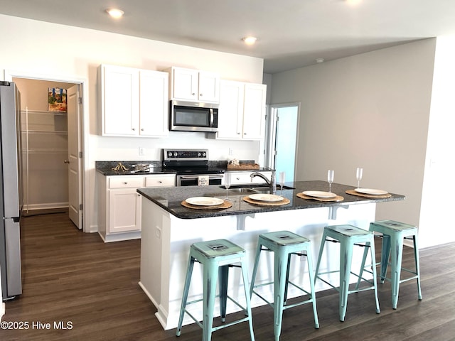 109 Mesa Ln, Holly Ridge, NC 28445 - kitchen with stainless steel appliances, a breakfast bar area, dark wood-style flooring, white cabinets, and recessed lighting