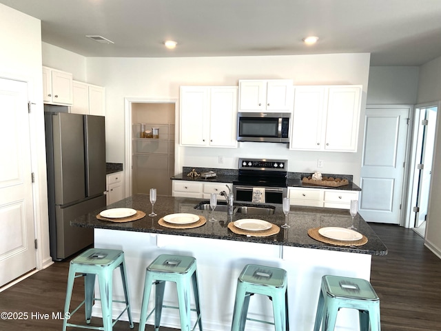 109 Mesa Ln, Holly Ridge, NC 28445 - kitchen with appliances with stainless steel finishes, a kitchen breakfast bar, white cabinetry, dark wood-style flooring, and dark stone counters