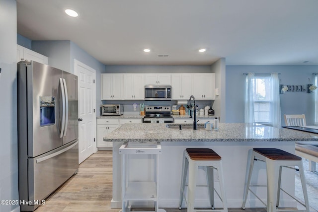 870 Westway Rd, Southport, NC 28461 - kitchen with appliances with stainless steel finishes, a breakfast bar area, white cabinets, light stone counters, and recessed lighting