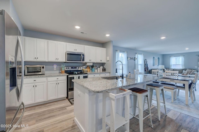 870 Westway Rd, Southport, NC 28461 - kitchen featuring appliances with stainless steel finishes, light wood-style floors, white cabinets, light stone counters, and recessed lighting