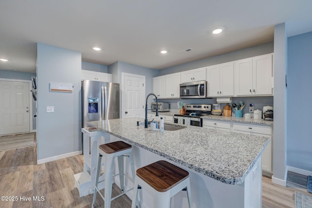 870 Westway Rd, Southport, NC 28461 - kitchen featuring stainless steel appliances, white cabinetry, a center island with sink, light wood finished floors, and recessed lighting