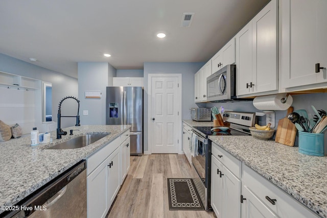 870 Westway Rd, Southport, NC 28461 - kitchen featuring appliances with stainless steel finishes, white cabinetry, light wood-style flooring, light stone countertops, and recessed lighting