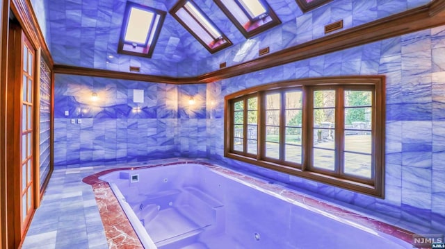 bathroom with tiled bath, a skylight, and tile walls