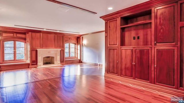 unfurnished living room with crown molding and light hardwood / wood-style floors