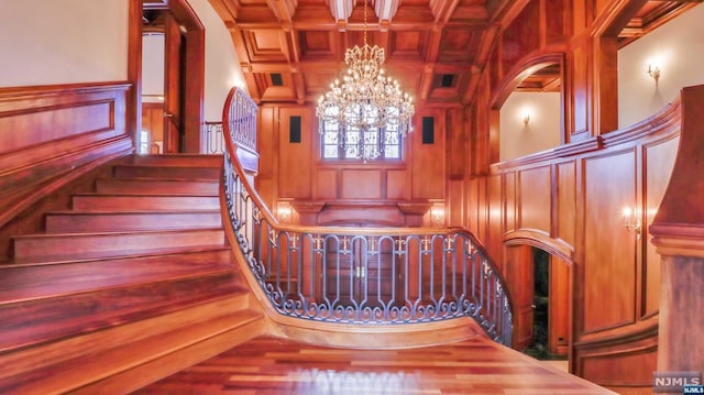 stairs with beamed ceiling, hardwood / wood-style flooring, coffered ceiling, and wood walls