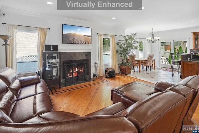 living room with light hardwood / wood-style floors, a premium fireplace, crown molding, and a chandelier