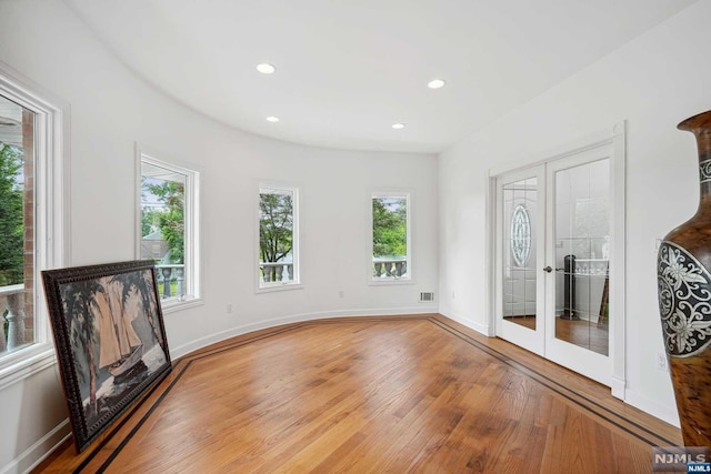 unfurnished living room featuring hardwood / wood-style floors and french doors