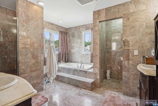 bathroom featuring shower with separate bathtub, vanity, and tile walls