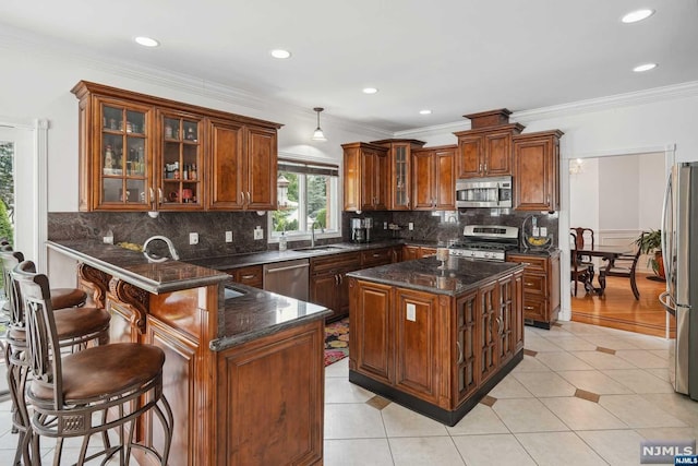 kitchen featuring sink, light tile patterned floors, ornamental molding, a kitchen island, and stainless steel appliances