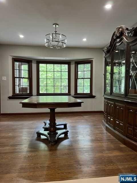 miscellaneous room featuring dark wood-type flooring and a notable chandelier