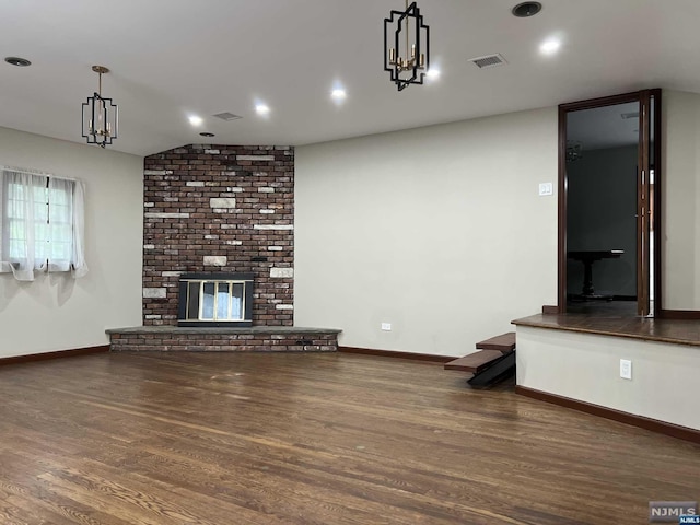 unfurnished living room featuring vaulted ceiling, dark hardwood / wood-style flooring, and a brick fireplace