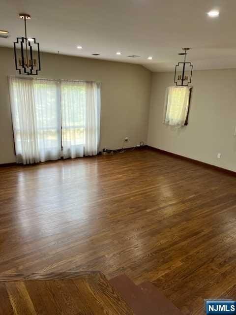 empty room featuring dark wood-type flooring and an inviting chandelier