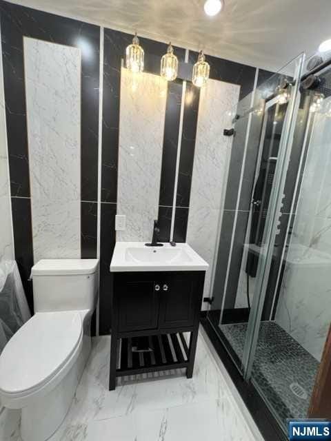 bathroom with vanity, toilet, and a shower with door