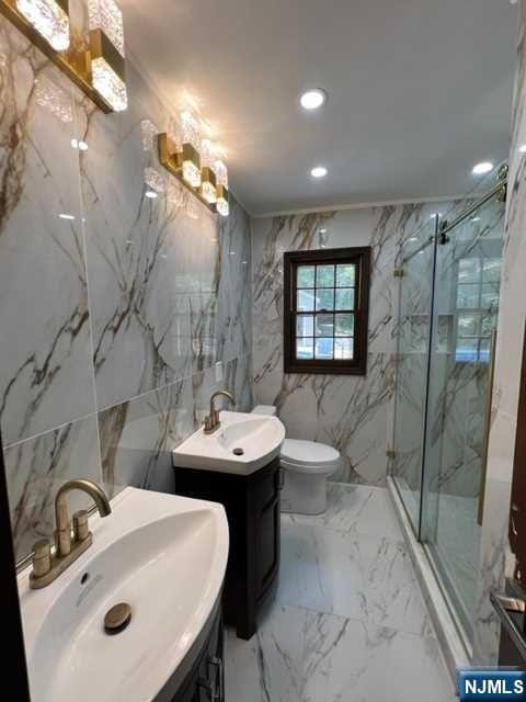 bathroom with an enclosed shower, vanity, and tile walls