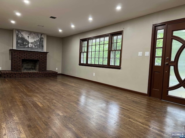 unfurnished living room with a fireplace, a wealth of natural light, and dark wood-type flooring