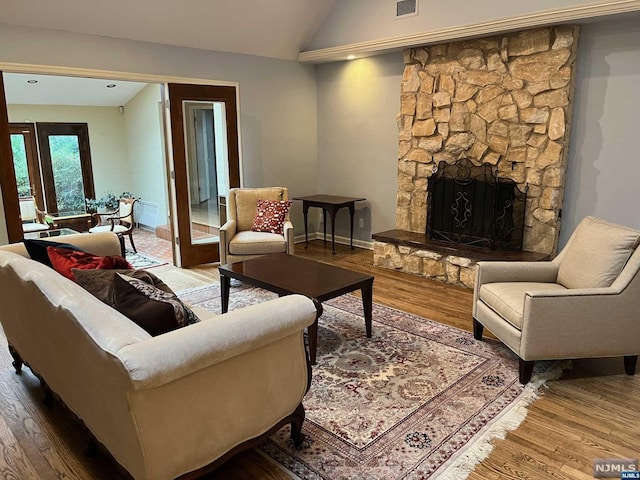 living room with a fireplace, hardwood / wood-style floors, and vaulted ceiling