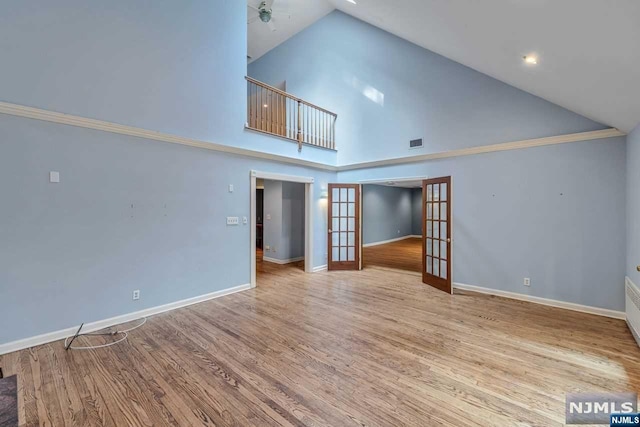 unfurnished living room featuring french doors, light hardwood / wood-style floors, high vaulted ceiling, and ceiling fan