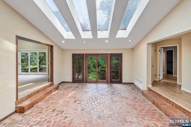 interior space with lofted ceiling with skylight, plenty of natural light, and radiator heating unit