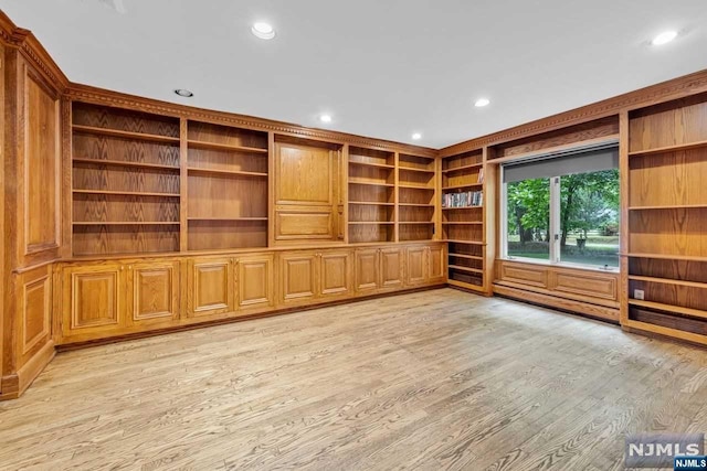 unfurnished living room featuring built in shelves and light hardwood / wood-style flooring