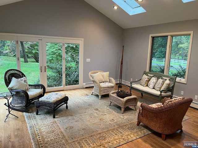 living room featuring baseboard heating, a skylight, high vaulted ceiling, and light wood-type flooring