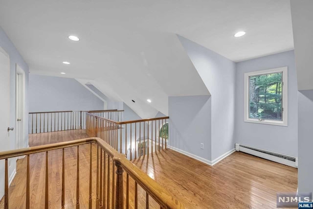 interior space featuring light hardwood / wood-style floors, lofted ceiling, and a baseboard radiator