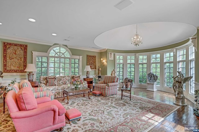 living room featuring crown molding, an inviting chandelier, a healthy amount of sunlight, and hardwood / wood-style flooring