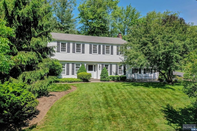 colonial home featuring a front lawn