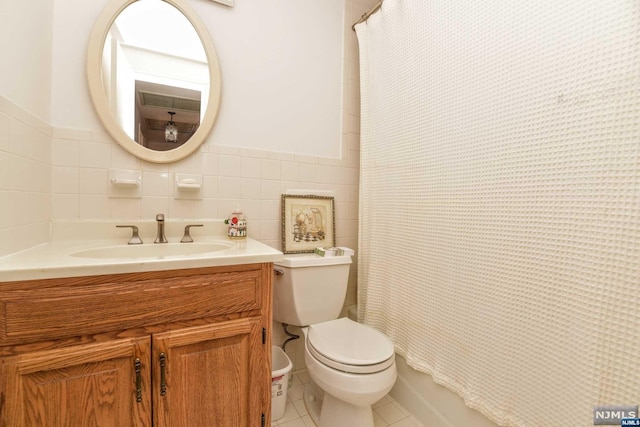 bathroom featuring tile patterned floors, vanity, toilet, and tile walls