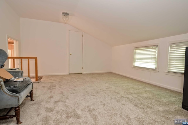 living area featuring light carpet and vaulted ceiling