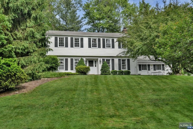 colonial-style house featuring a front yard