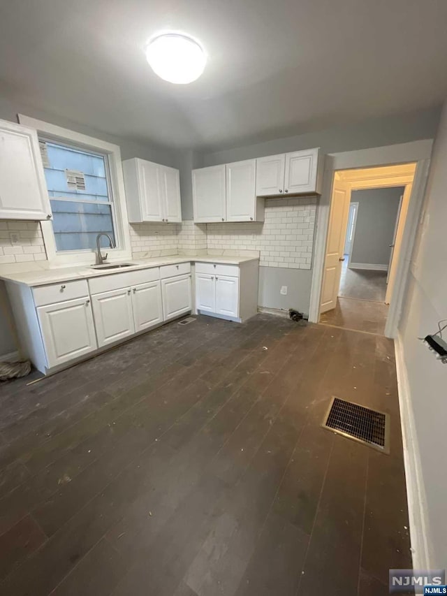 kitchen with dark hardwood / wood-style floors, decorative backsplash, white cabinetry, and sink