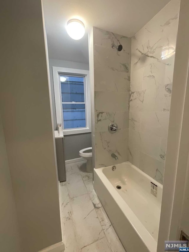 bathroom featuring tiled shower / bath combo and toilet