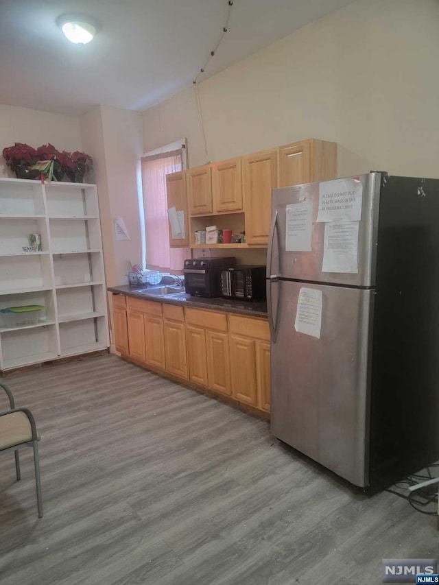 kitchen with light wood-type flooring, sink, and stainless steel refrigerator