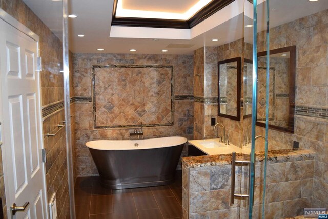 bathroom featuring vanity, tile patterned flooring, separate shower and tub, tile walls, and a tray ceiling