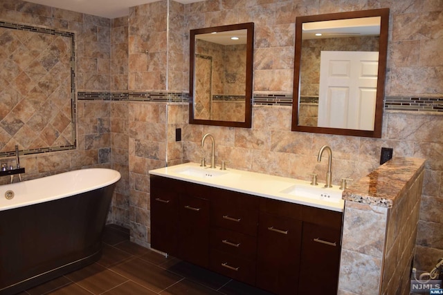 bathroom featuring a washtub, vanity, and tile walls