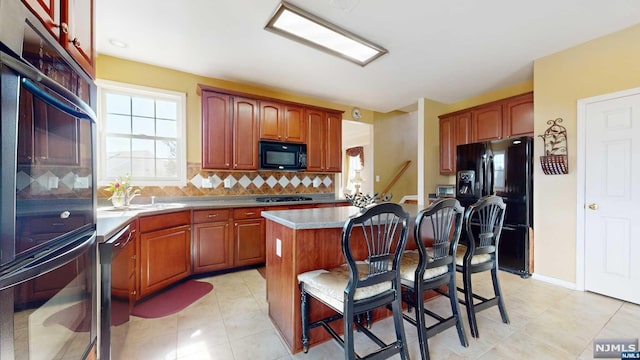 kitchen featuring black appliances, a kitchen breakfast bar, light tile patterned floors, tasteful backsplash, and a kitchen island