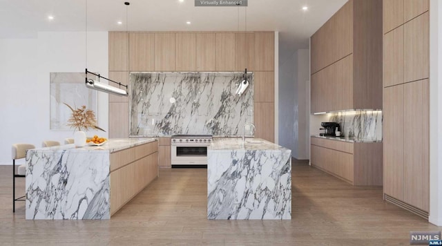 kitchen with high end range, light brown cabinets, light hardwood / wood-style flooring, and a large island