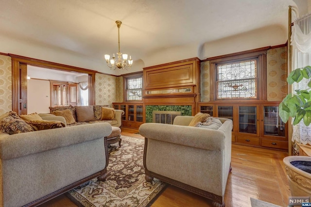 living room with a tile fireplace, light hardwood / wood-style floors, and a notable chandelier