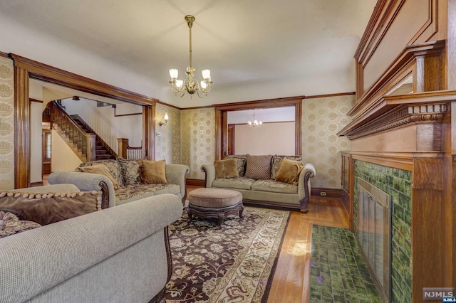 living room with a tile fireplace, hardwood / wood-style flooring, and an inviting chandelier