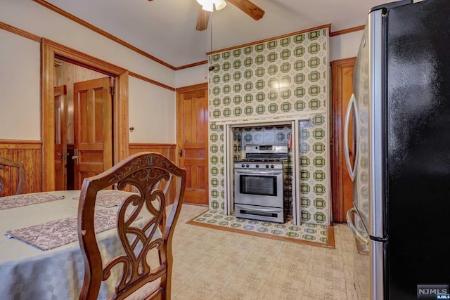 kitchen featuring stainless steel appliances, ceiling fan, ornamental molding, and wood walls