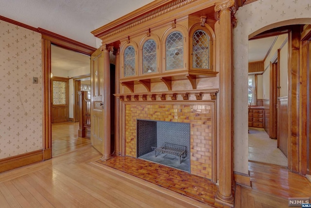 unfurnished living room featuring crown molding, a fireplace, light hardwood / wood-style floors, and a textured ceiling